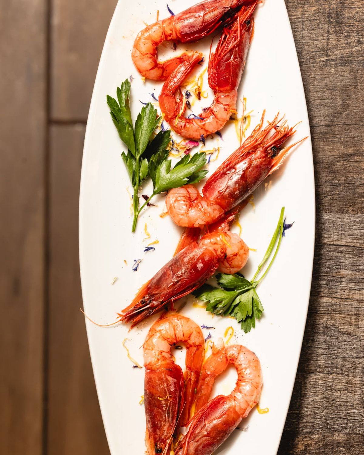 Red prawns dressed with herbs and citrus on a long plate