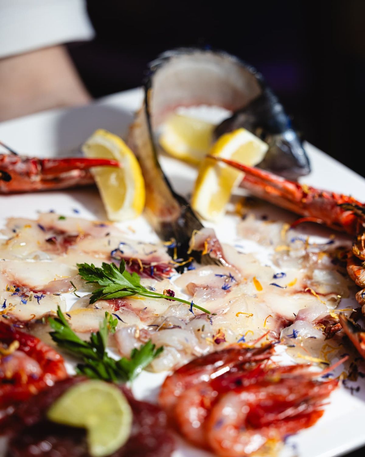 A mixed raw seafood platter with lemon and prawns