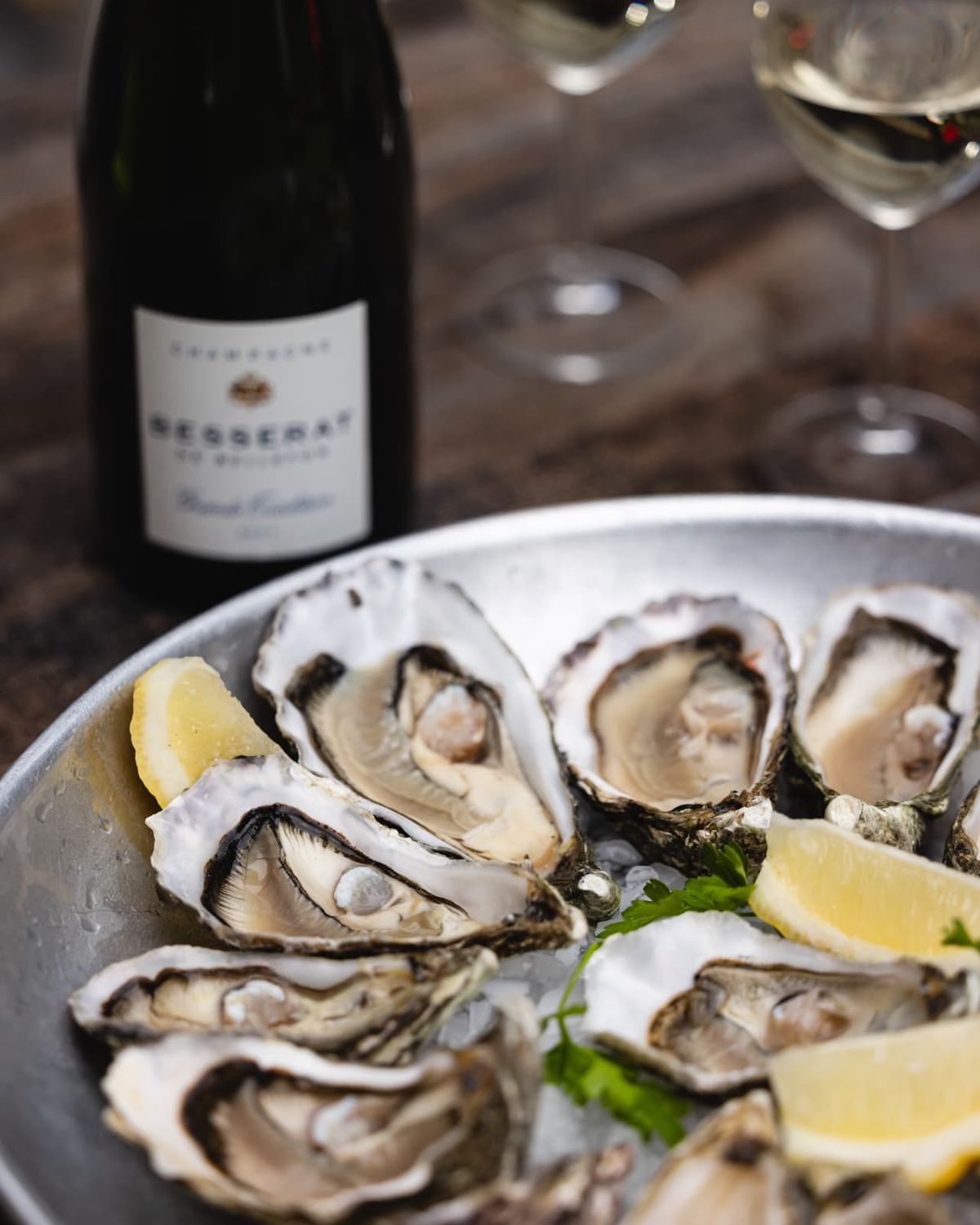 A platter of fresh oysters beside a bottle of Champagne
