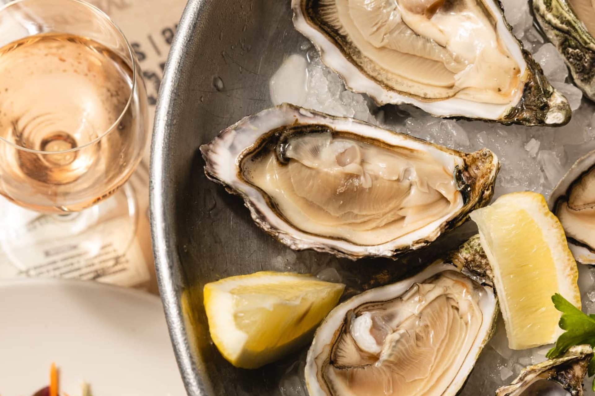 Freshly shucked oysters on ice with lemon and a glass of rosé